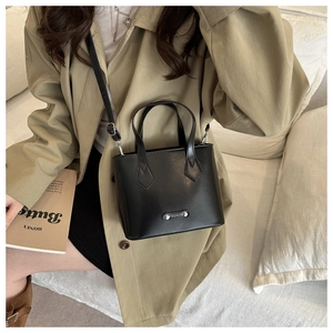 Fashionable black faux leather bucket bag shown being worn by a model in a cozy room