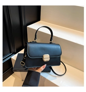 Close-up of minimalist black leather crossbody bag with elegant square gold buckle clasp
