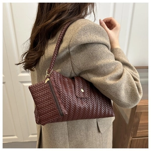 Detail of burgundy woven underarm bag featuring intricate braided faux leather texture