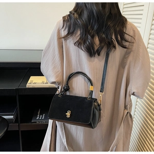 Detail of suede crossbody bag with gold twist lock on purple pleated dress outfit