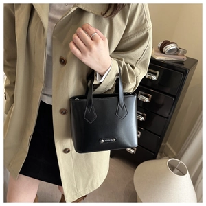 Close-up of black textured leather bucket bag featuring silver Fashion metal plaque detail