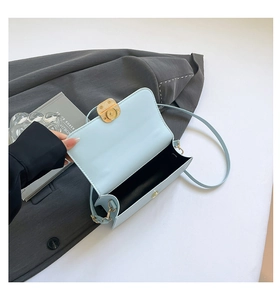 Detail of light blue crossbody bag featuring gold magnetic snap closure and interior lining