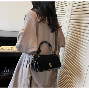 Detail of black suede patchwork handbag with golden twist lock and thin shoulder strap