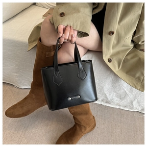 Detail of minimalist black matte leather tote bag with silver Fashion metal plaque