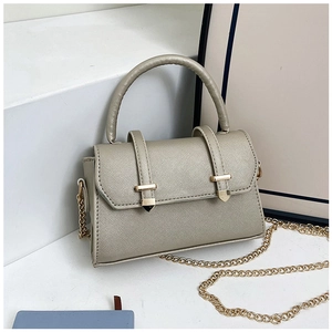 Gros plan du sac en cuir Saffiano doré champagne avec bandoulière sur support minimaliste