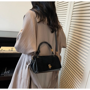 Detail of suede flap and leather body contrast with gold twist lock on black handbag