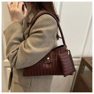 Detail of woven burgundy shoulder bag with matching mini pouch on a model side view