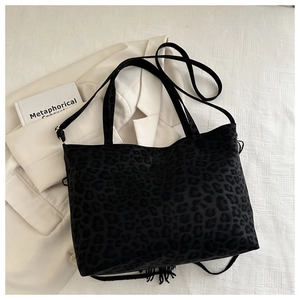 Dettaglio della borsa tote leopardata nera con frange su tessuto bianco operato