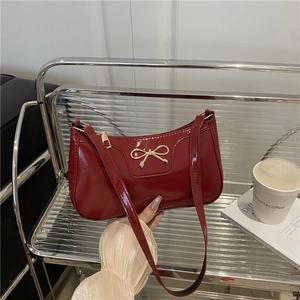 Chic burgundy patent leather baguette bag with golden bow accent for elegant shoulder wear