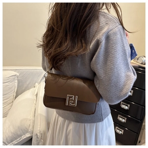 Dettaglio della borsa a tracolla in pelle marrone con chiusura geometrica in oro sulla patta