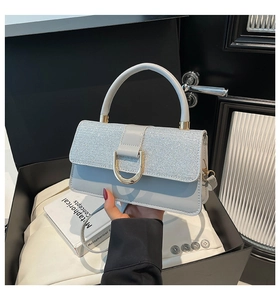 Detail of glitter flap and gold D-buckle on a light grey-blue leather handbag