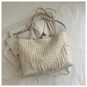 Dettaglio della borsa tote bohémien beige intrecciata con nappe e tracolla su tessuto