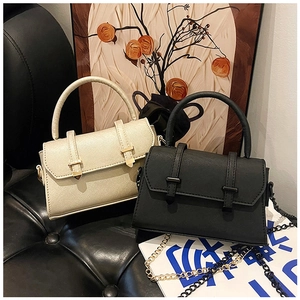 Détail de mini sacs à bandoulière en cuir champagne et noir avec chaînes métalliques