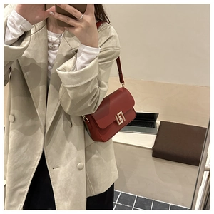 Selfie allo specchio che mostra le dimensioni di una piccola borsa a tracolla in pelle rossa