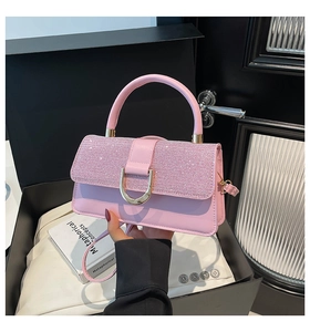 Close-up of pink leather handbag featuring glitter sequins and gold D-ring hardware