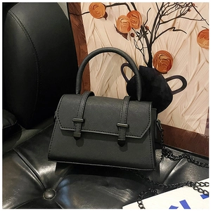 Détail de la texture du cuir Saffiano noir et de la double boucle de fermeture du sac