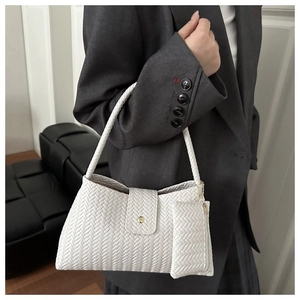 Detailed woven texture of a white underarm bag with small pouch worn with a blazer