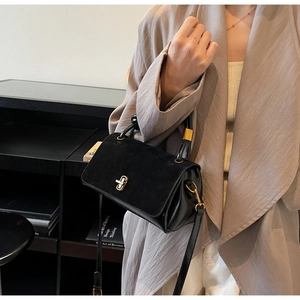 Detail of black suede and leather crossbody bag with golden twist lock and top handle