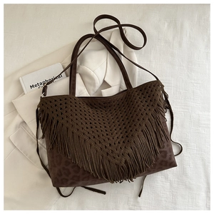 Dettaglio borsa tote marrone all'uncinetto con nappe e base leopardata su blazer