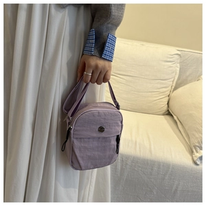 Close-up of lavender nylon crossbody bag with durable pleated fabric and metal logo
