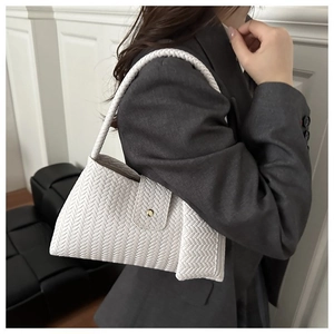 Close-up of white woven shoulder bag on model showing fine texture and metallic closure