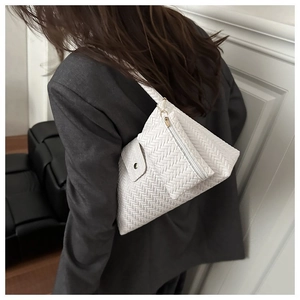 Detail of white woven underarm bag on model, featuring a stylish 2-in-1 pouch set