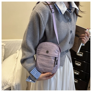 Detail of lavender nylon crossbody bag with adjustable strap shown in home setting