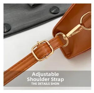 Detail of adjustable tan leather shoulder strap with polished gold-tone metal buckle