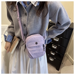 Light purple nylon crossbody bag with adjustable strap worn by model in casual style