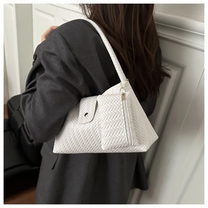 Detail of white woven underarm bag texture with matching mini zipper pouch accessory