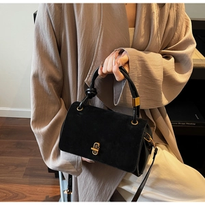 Detail of black suede and smooth leather bag with golden hardware and twist lock