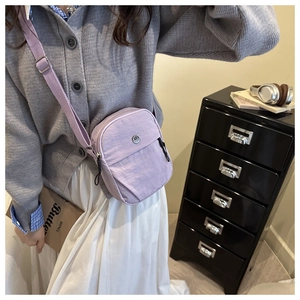 Detailed view of a purple nylon crossbody bag with adjustable strap worn by a model