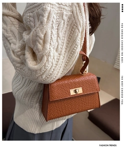 Détail du sac à main marron motif crocodile avec fermoir rotatif doré élégant