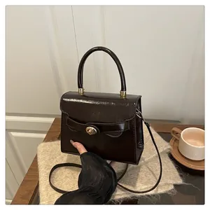 Glossy brown patent leather handbag with gold twist lock on a rustic wooden table