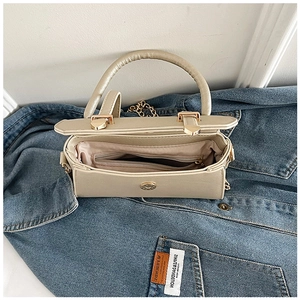 Détail du compartiment intérieur et de la chaîne dorée d'un sac sous le bras beige