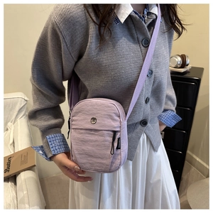 Close-up of a purple nylon crossbody bag with dual zippers and adjustable fabric strap