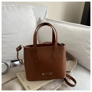 Detailed close-up of brown faux leather bucket bag texture and silver FASHION metal logo