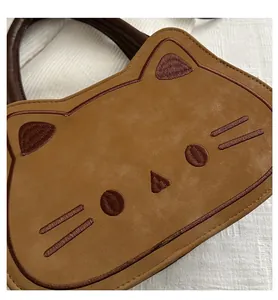 Detail of cute cat shaped crossbody bag showing brown suede fabric and fine embroidery