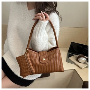 Close-up of brown woven shoulder bag with mini pouch and braided strap in a lifestyle set