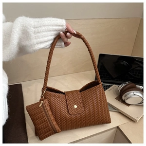 Detail of woven texture on caramel brown underarm bag with small square pouch