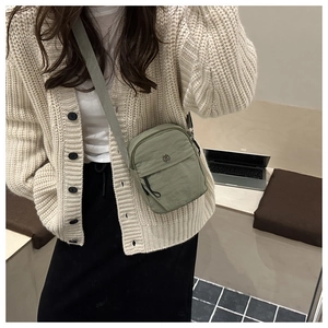 Detail view of olive green nylon crossbody bag with adjustable wide strap and metal buckle
