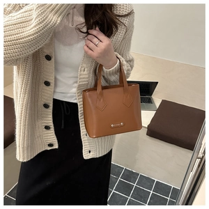 Detail of caramel leather bucket bag with fashion metal plate and smooth texture