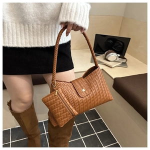 Detail of brown woven underarm bag with matching mini pouch on a modern model outfit
