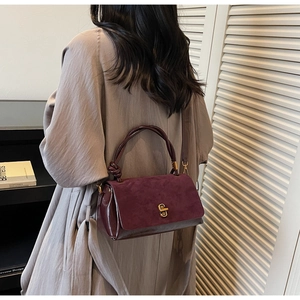 Detail of suede crossbody bag with elegant knot handle and gold twist lock closure