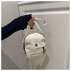 Detail of cream pleated nylon crossbody bag with metal logo and zipper closure