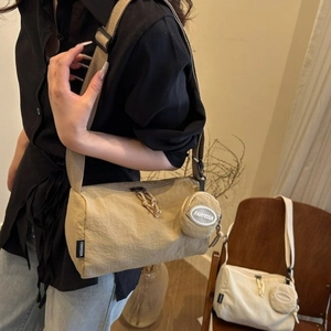 Détail du sac cylindrique en nylon kaki avec large bandoulière et petit porte-monnaie