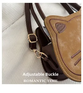 Detail of adjustable golden metal buckle and cute cat embroidery on brown shoulder bag