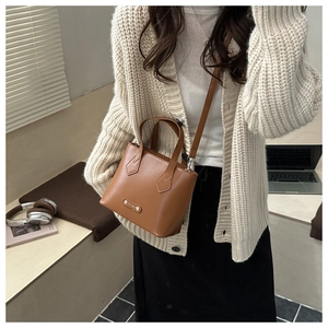 Close-up of caramel PU leather mini bucket bag with silver nameplate and dual handles