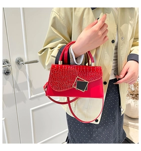 Detail of red crocodile texture flap handbag with sleek gold metal buckle and handle