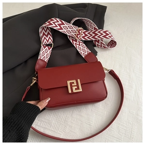 Dettaglio della borsa a tracolla in pelle rossa con fibbia dorata e doppia tracolla